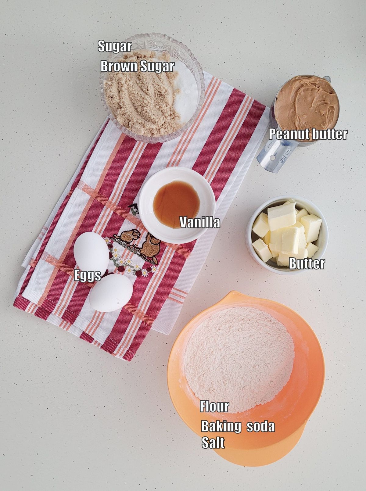 overhead view of ingredients needed to make peanut butter cookie dough including flour, baking soda, salt, peanut butter, egg, butter and brown and granulated sugar