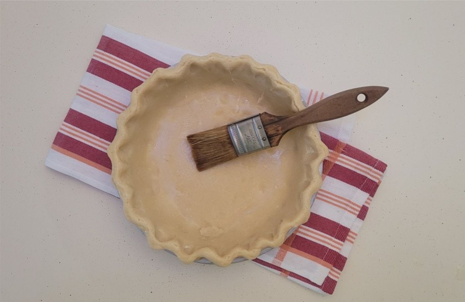 pie crust and pastry brush with egg brushed on it to prevent burning