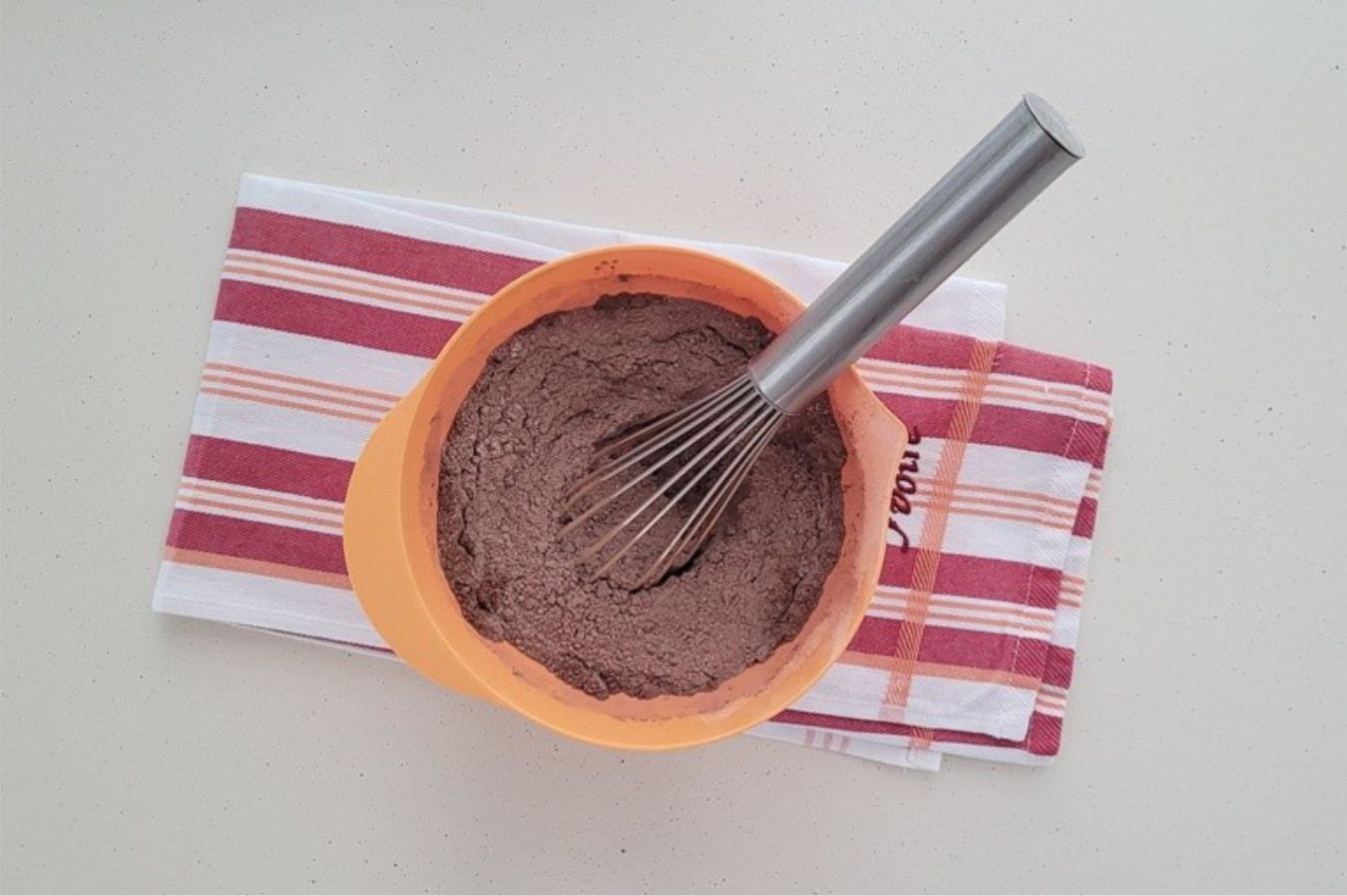bowl with whisk and dry ingredients including flour, salt, baking soda and cocoa powder