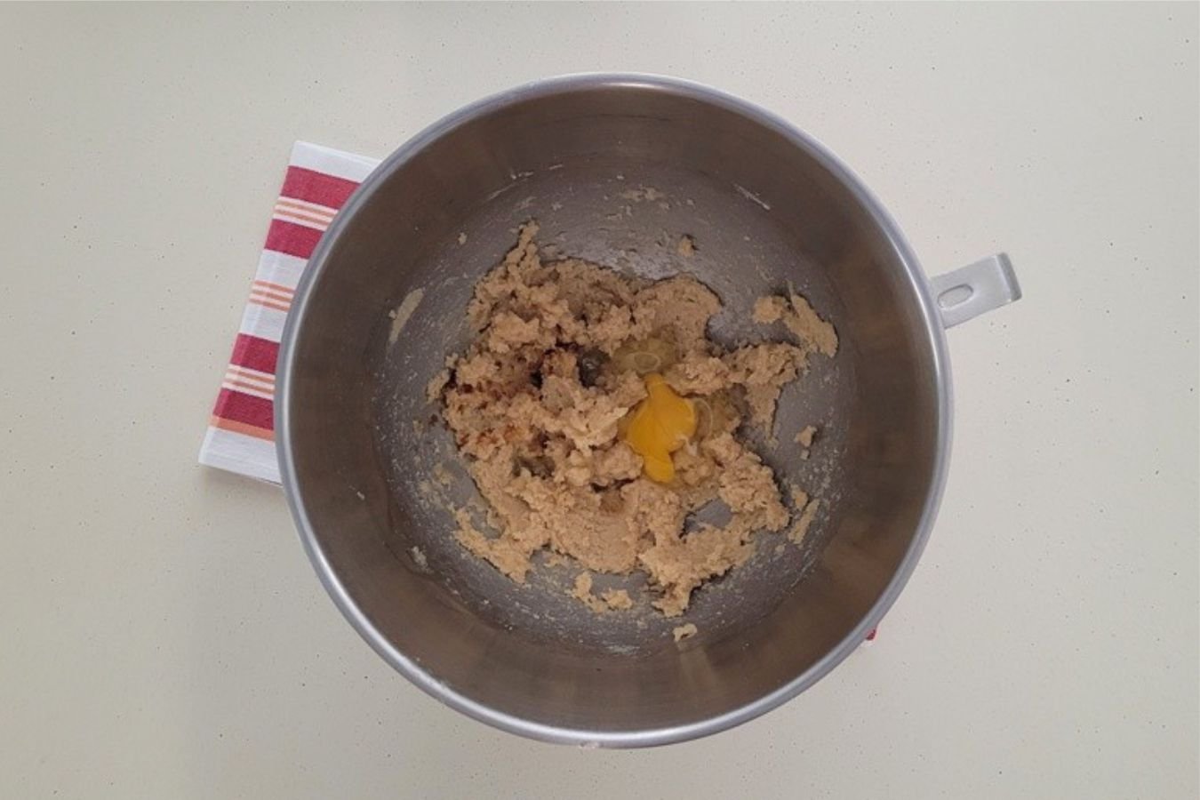 overhead view of egg added to mixing bowl to make chocolate cookie dough