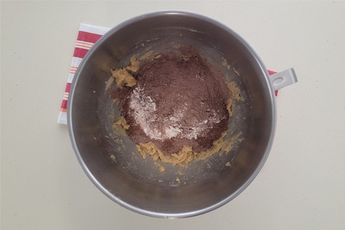 overhead view of dry ingredients added to mixing bowl to make chocolate cookie dough