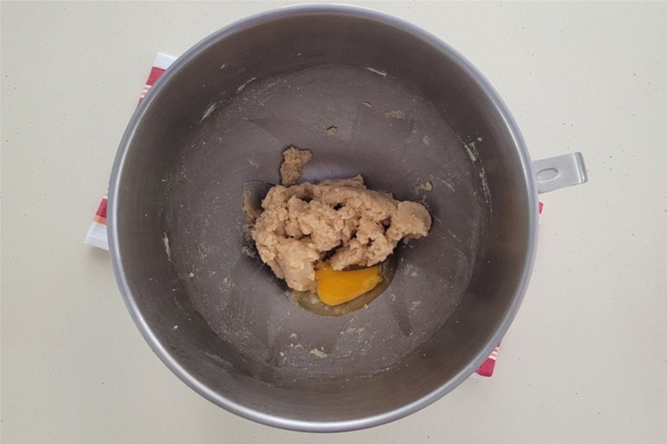 overhead view of mixing bowl with egg added to creamed butter and sugars