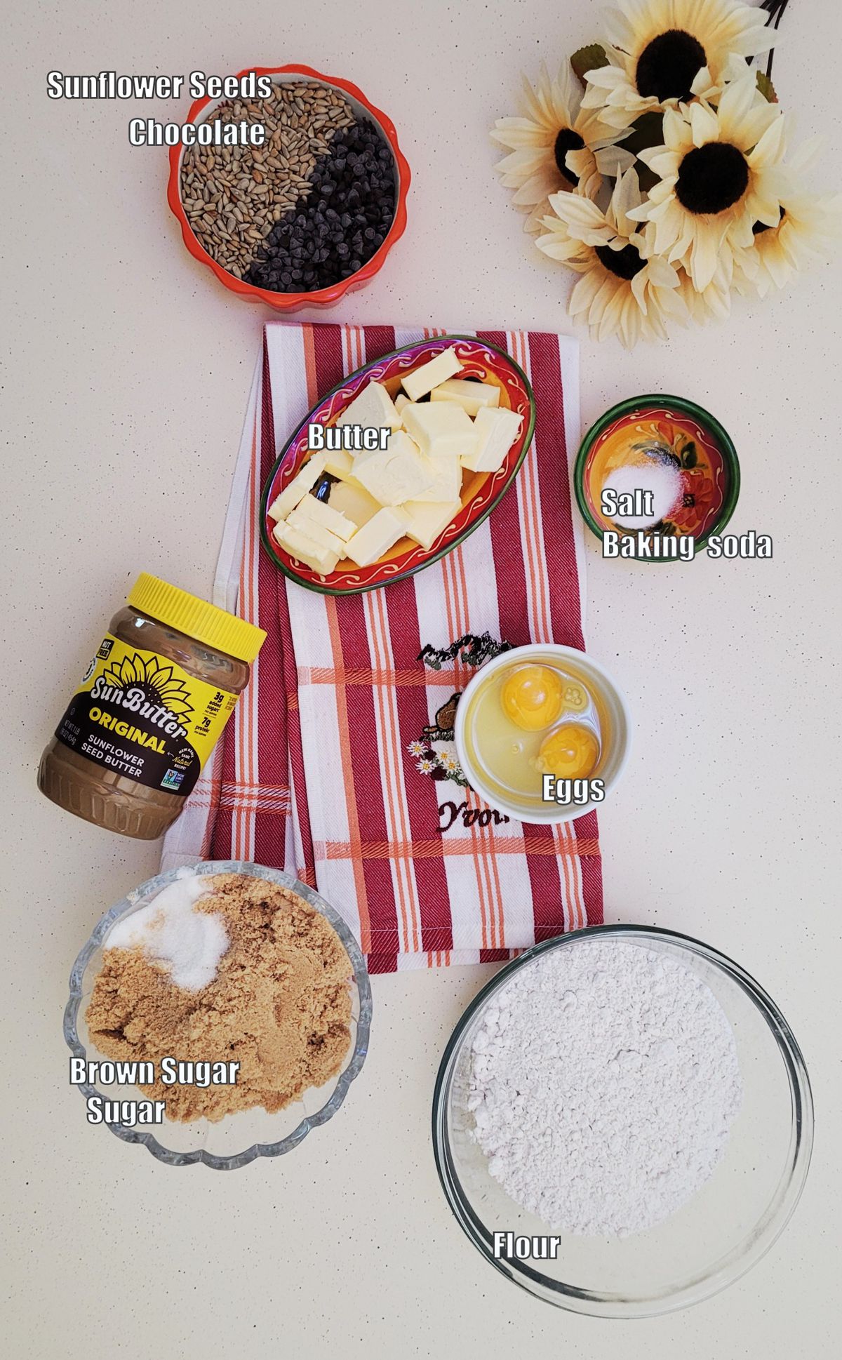 overhead view of ingredients needed to make sunbutter cookie recipe including flour, brown sugar, granulated sugar, baking soda, salt, sunbutter, butter, eggs, chocolate chips and sunflower seeds