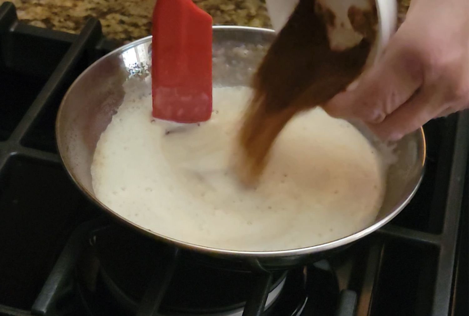 pouring espresso powder into a saucepan with browned butter