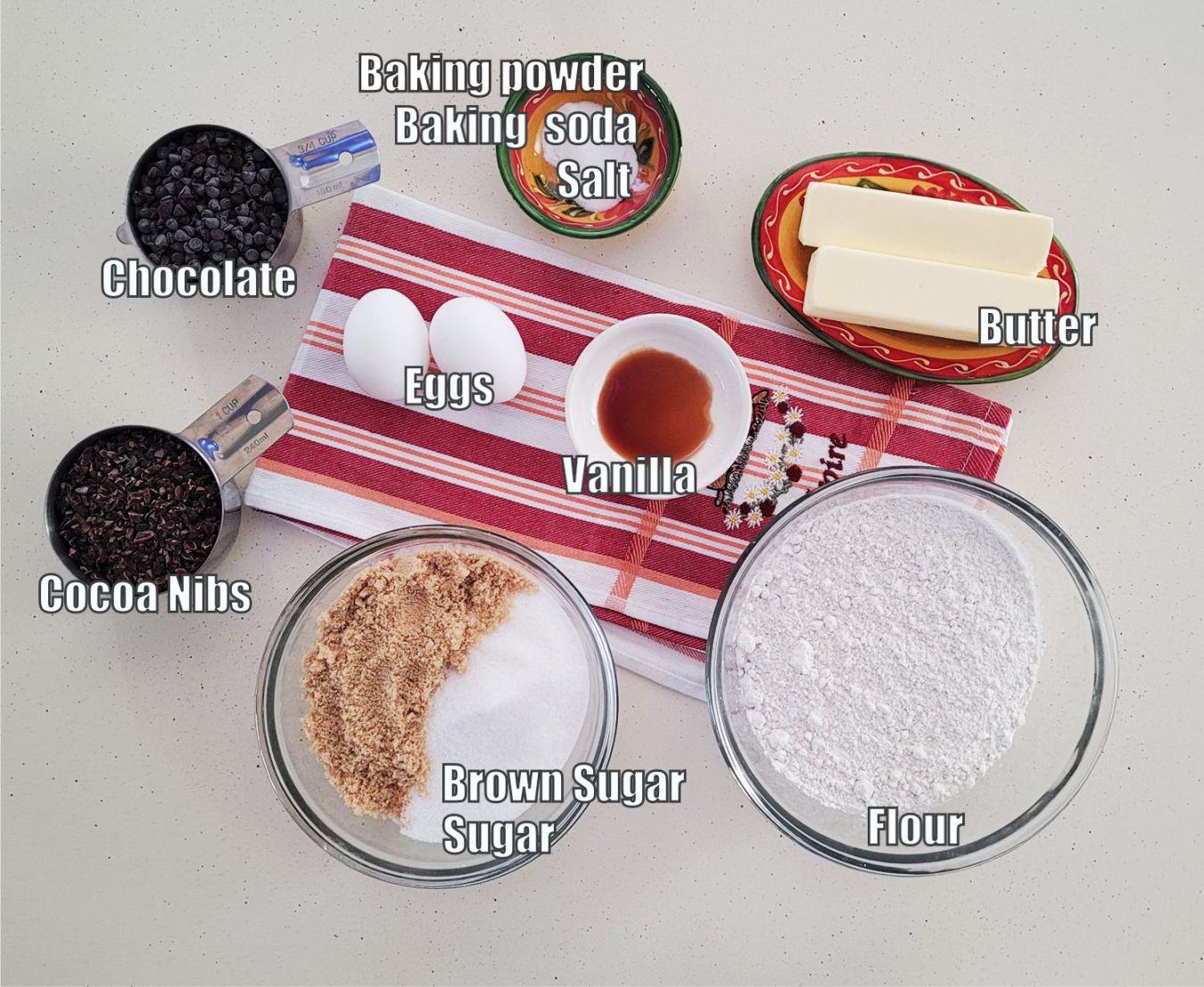 ingredients needed to make cocoa nibs cookie recipe including flour, brown sugar, granulated sugar, cocoa nibs, baking powder, baking soda, butter, eggs and vanilla extract