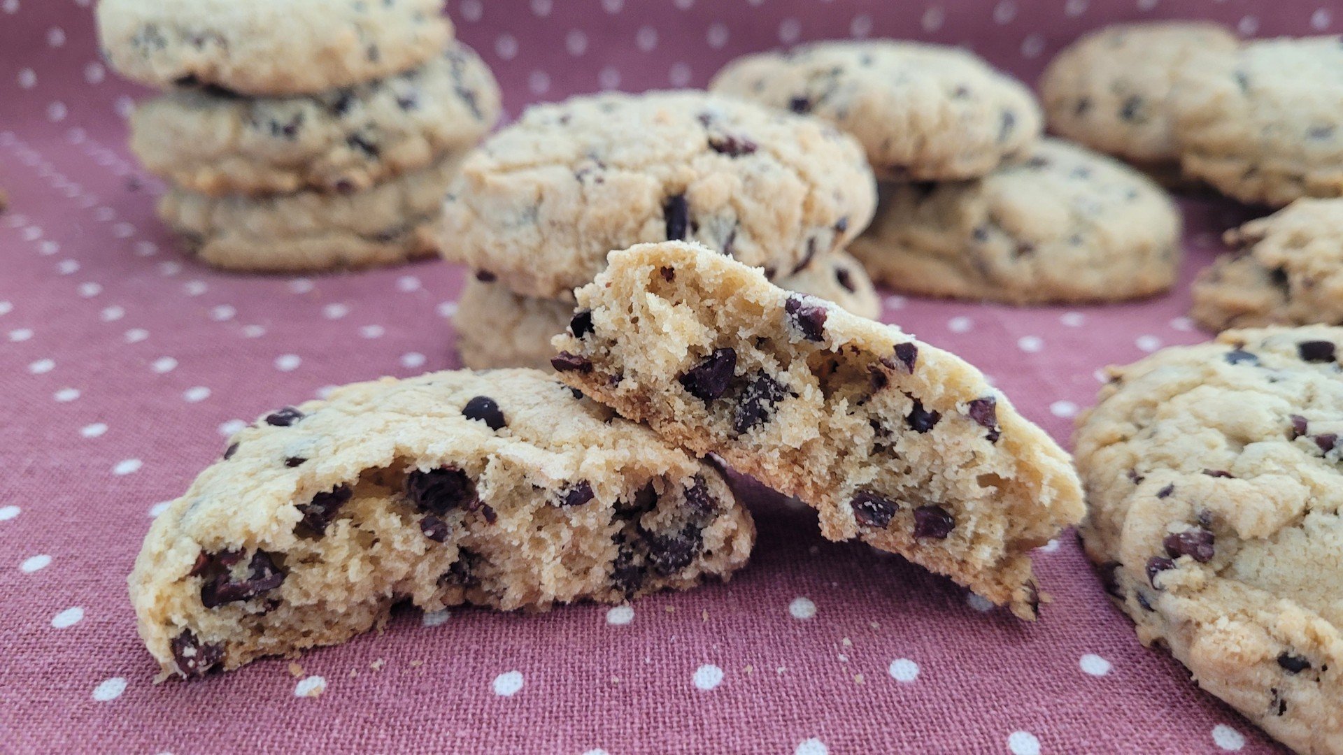 close up of cocoa nibs cookies with one cookie broken in half to show inside