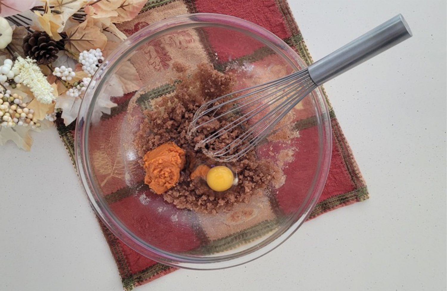 pumpkin puree and an egg added to mixing bowl with a whisk