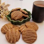 pumpkin spice latte cookies in a serving dish and on countertop with a cup of coffee and a fall-themed floral arrangement