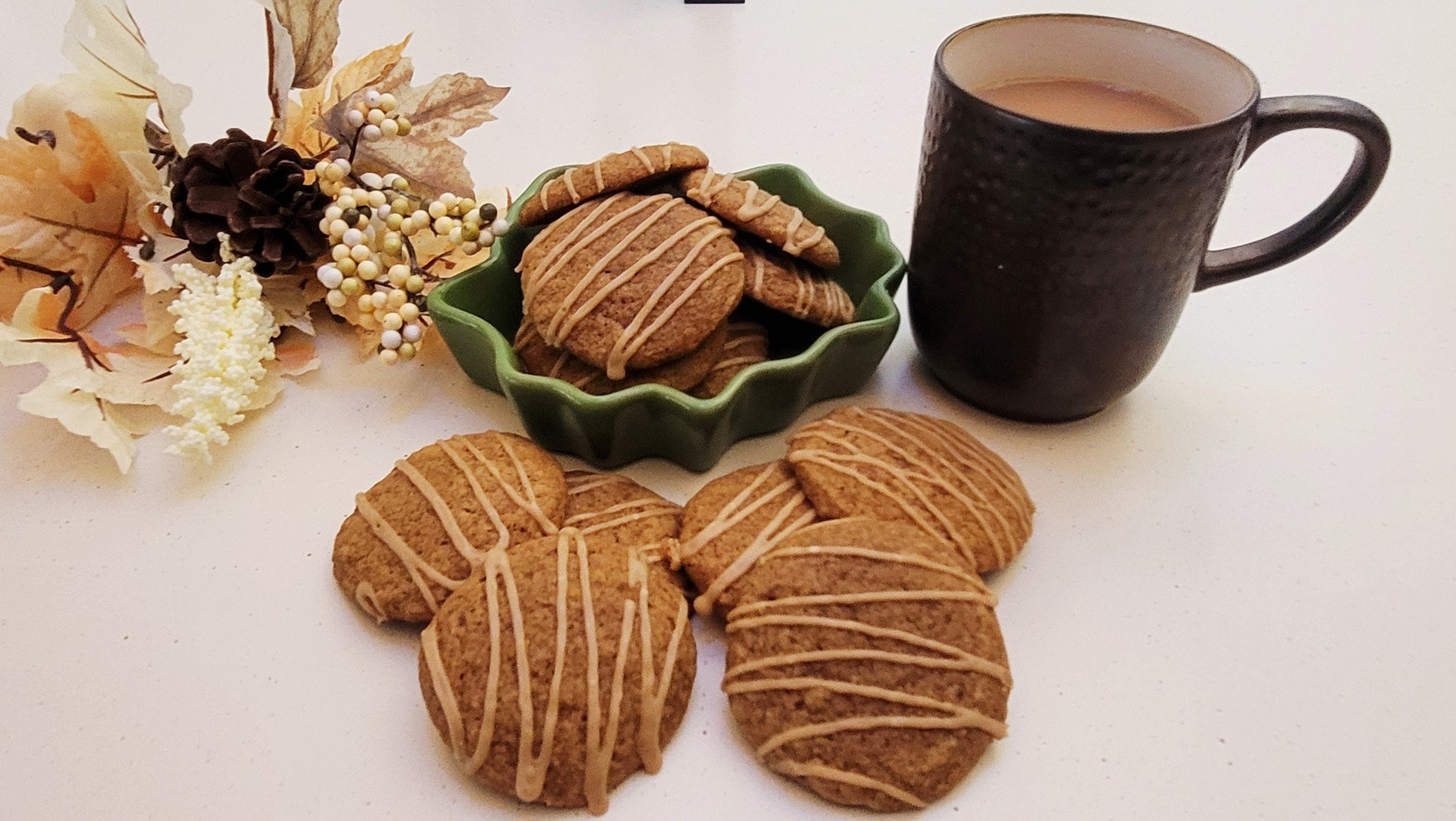pumpkin spice latte cookies in a serving dish and on countertop with a cup of coffee and a fall-themed floral arrangement