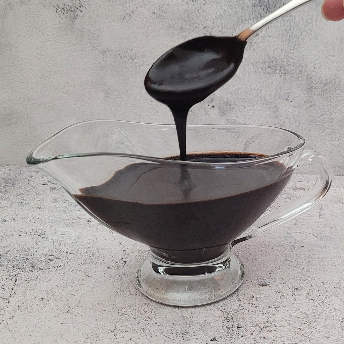 spoon drizzling chocolate sauce into a serving dish