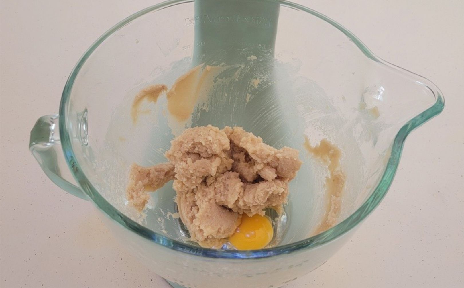 egg added to glass mixing bowl to make cookie dough