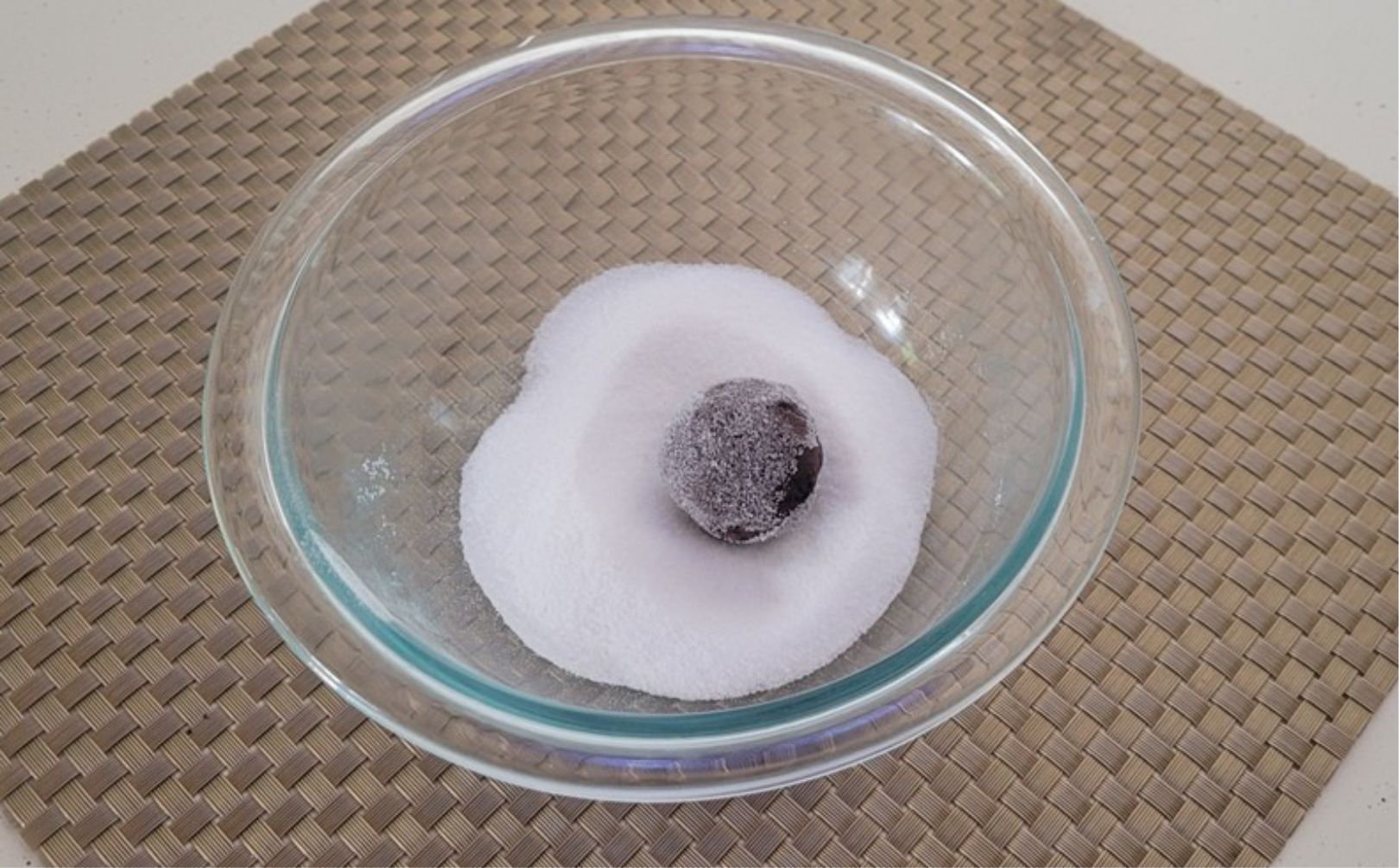 ball of gluten free crispy chocolate cookie dough in a bowl of granulated sugar