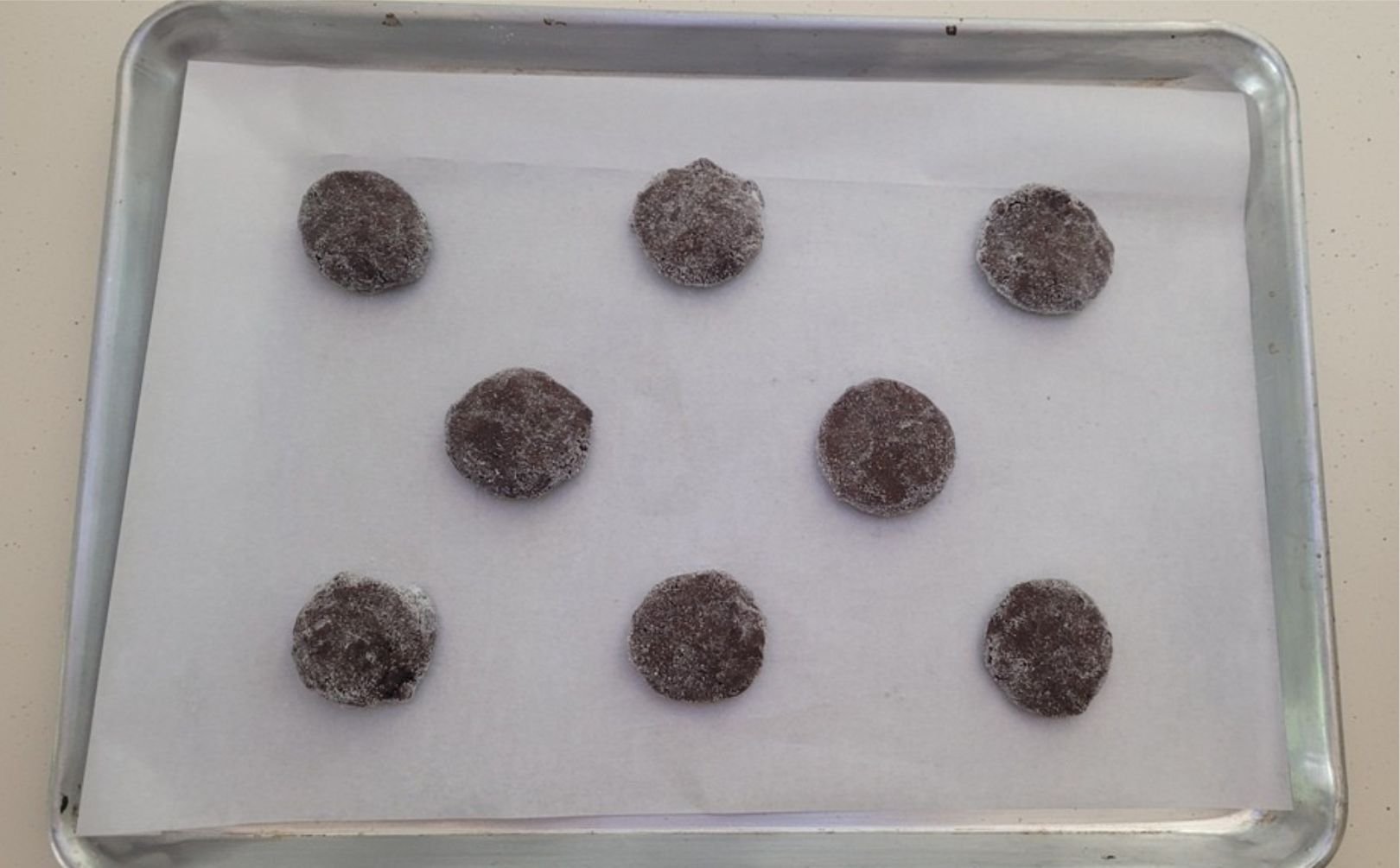 balls of crispy gluten free chocolate cookies scooped onto a baking pan