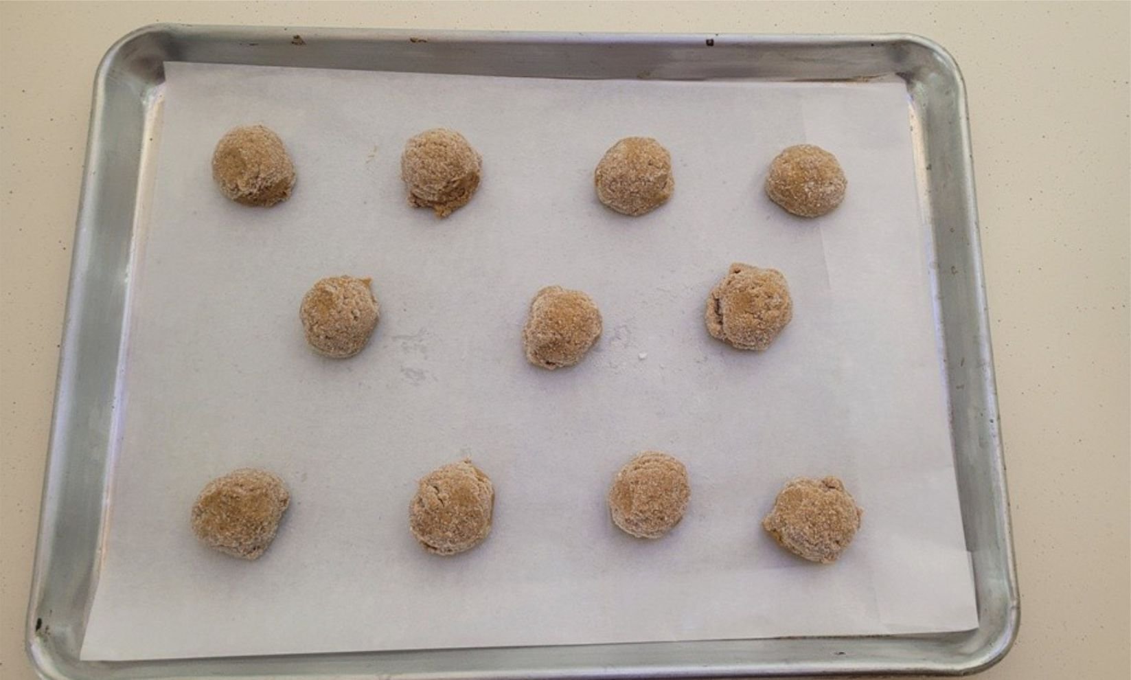 balls of ginger cookie dough on a sheet pan lined with parchment paper