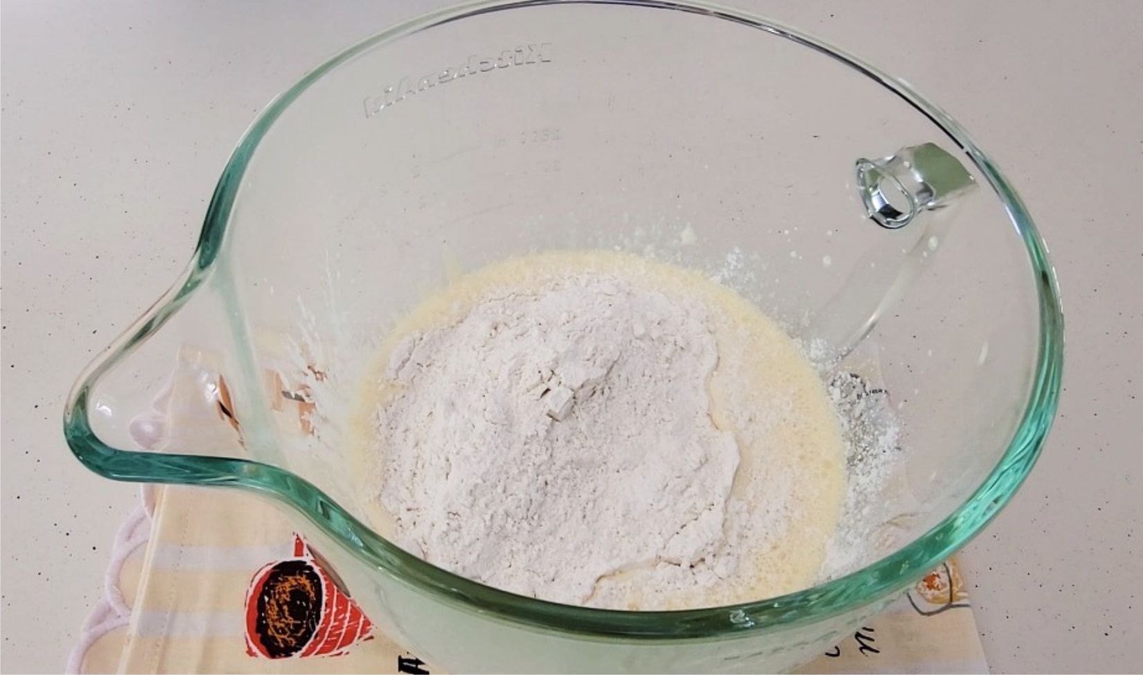 dry ingredients added to whipped egg yolks in a glass mixing bowl