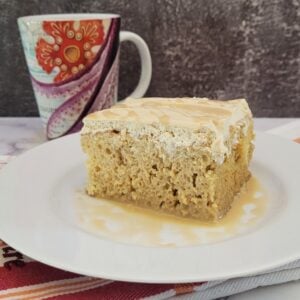 slice of coffee Tres Leches cake on a plate with coffee cup in background