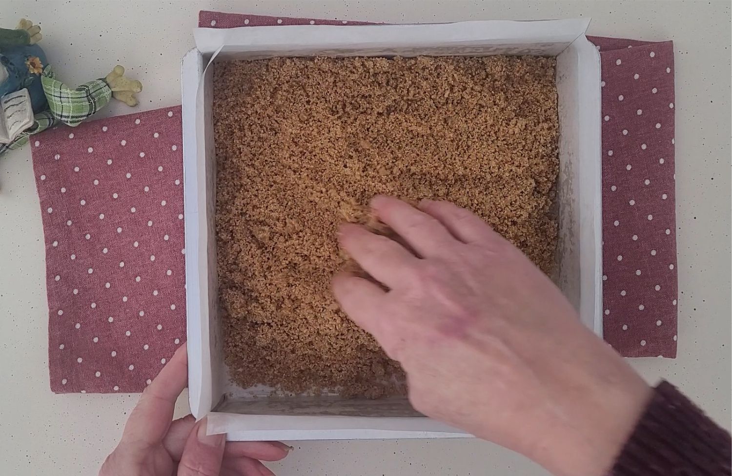 pressing graham cracker crust into baking pan as base for making Nutella swirl cheesecake bars