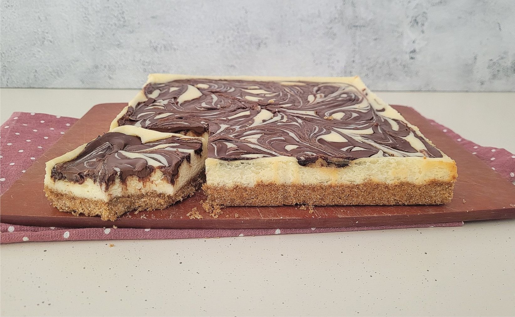 cheesecake bars with a Nutella swirl on a cutting board with one bar cut out