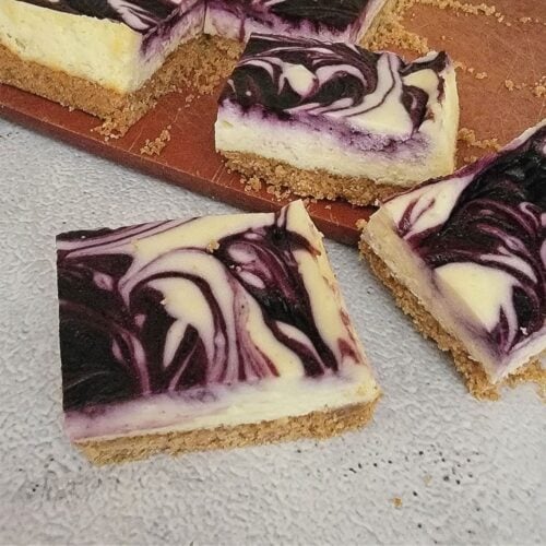 slices of blueberry swirl cheesecake bars on a countertop