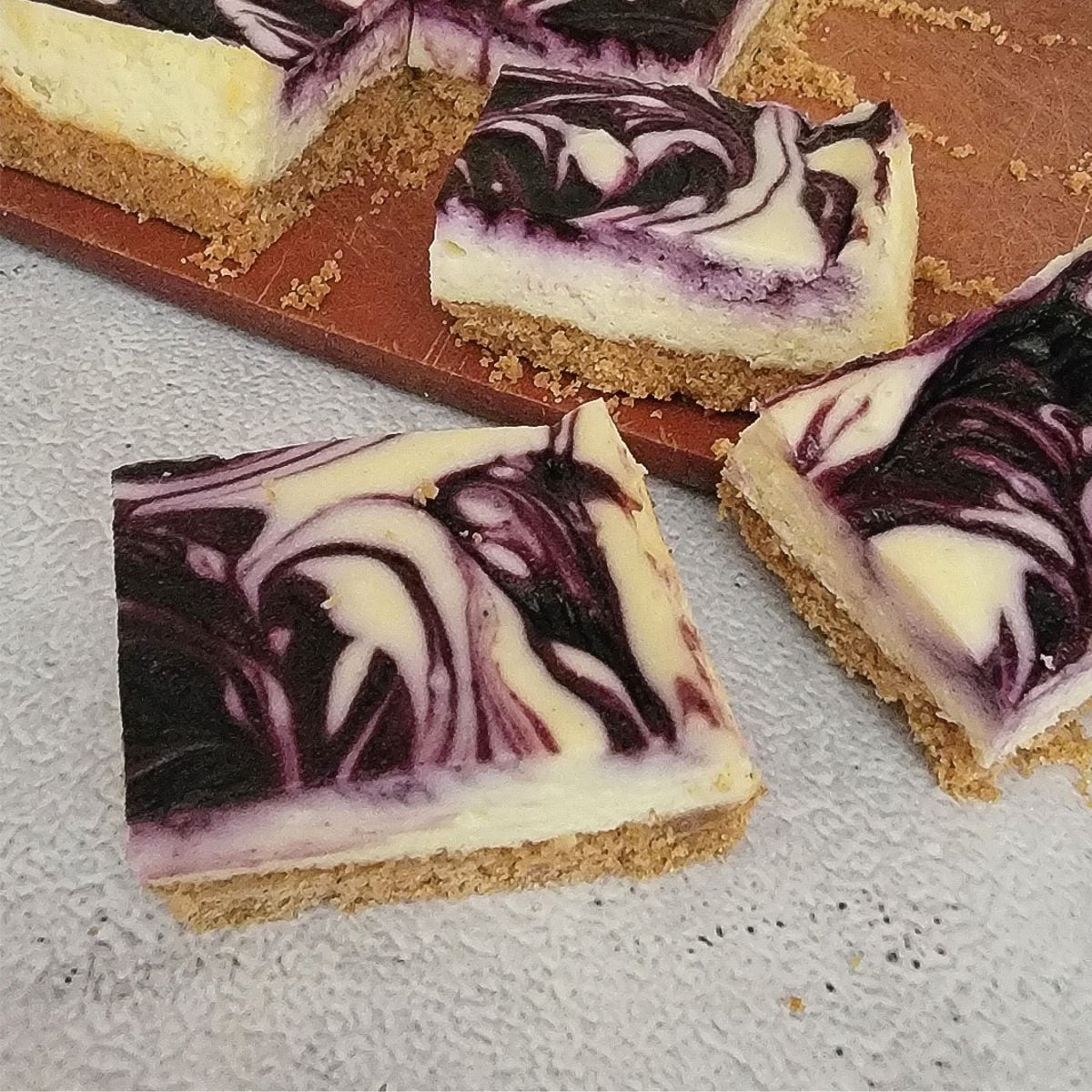 slices of blueberry swirl cheesecake bars on a countertop