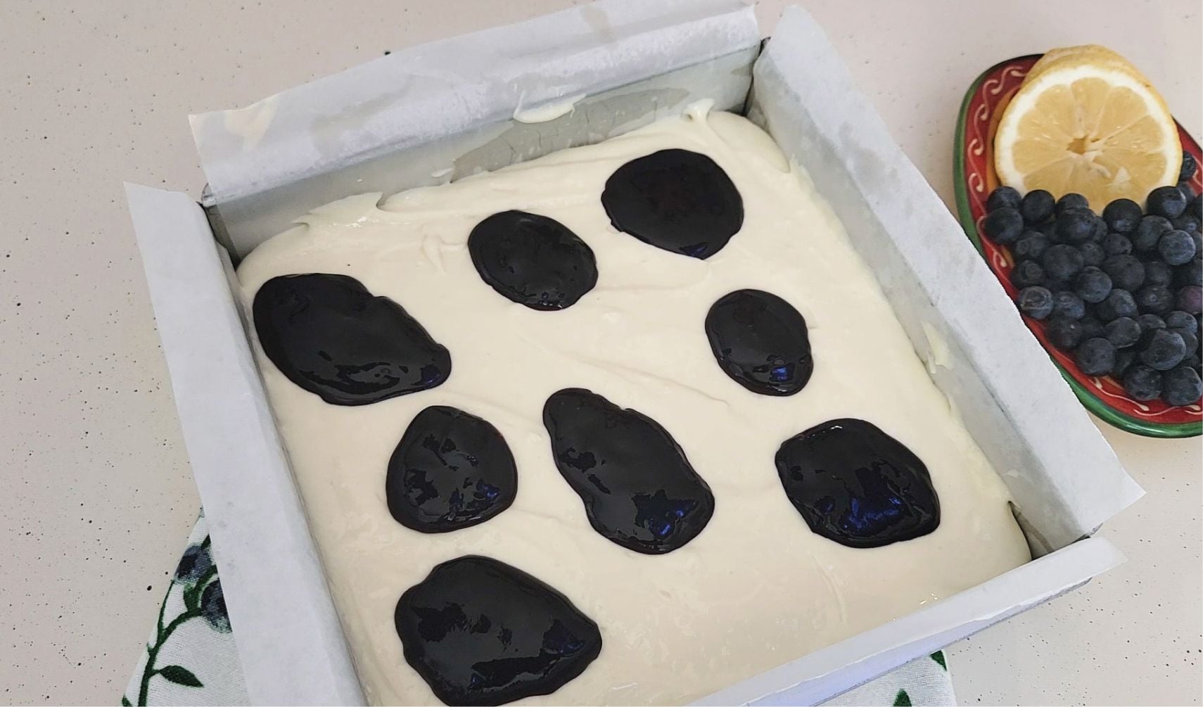 dollops of blueberry sauce randomly placed over cheesecake batter