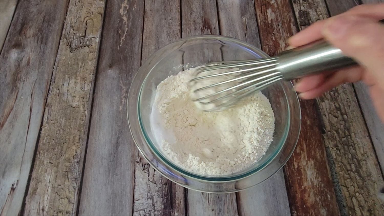 using a whisk to combine flour, salt and baking soda in a glass bowl