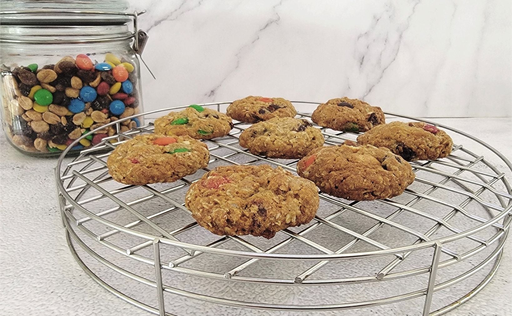 oatmeal cookies made with GORP ingredients on a rack and a jar of GORP in the background