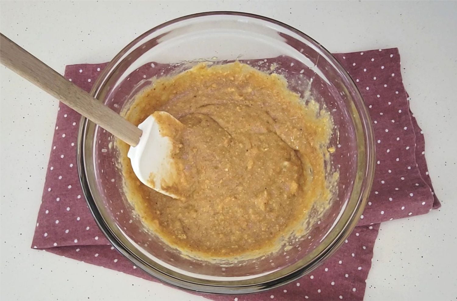 wet ingredients and protein powder mixed together in a glass bowl with a spatula