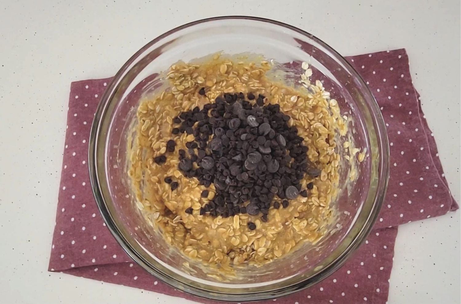 chocolate chips added to glass bowl with protein bars dough